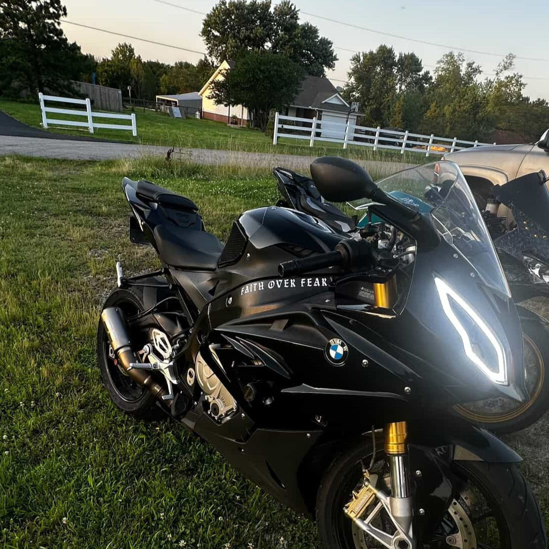 Black BMW motorcycle parked on grass with a car in the background